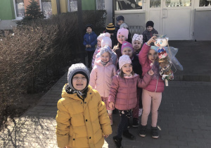 Dzieci stoją przed budynkiem przedszkolnym z Marzanną.